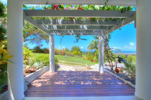 a white pergola with a view of the ocean at Domaine Les hauts de Sofaia - Évasion Créole - Vue Spectaculaire in Sofaïa