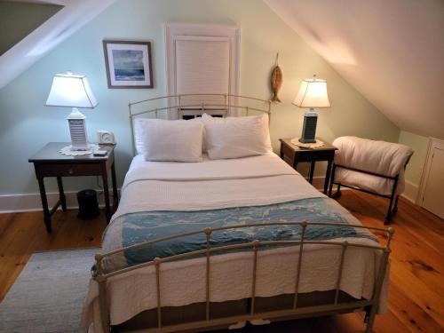 ein Schlafzimmer mit einem Bett mit zwei Lampen und zwei Stühlen in der Unterkunft Joy Cottage in Prospect Harbor