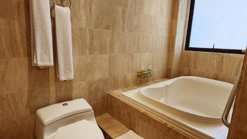 a bathroom with a toilet and a tub and a sink at Bogota Plaza Hotel in Bogotá