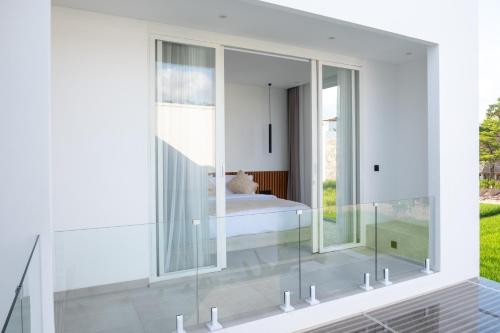 een glazen kamer met een bed en een raam bij White Palm Villa in Canggu