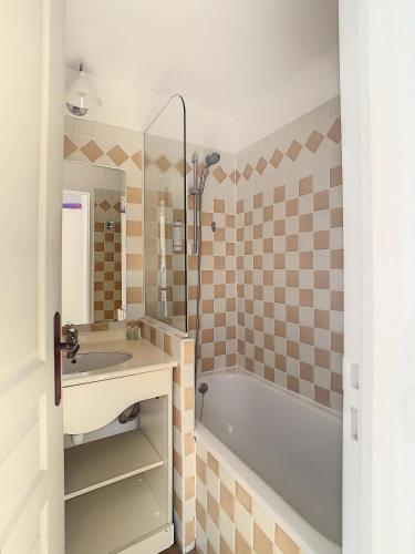 une salle de bain avec une baignoire, un lavabo et un miroir dans l'établissement Francia - T2 30m2 - Piscine - Vue mer, à Cannes