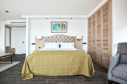 a bedroom with a large bed and a chair at Casa Mimosa Hotel in Karaburun