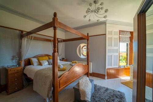 a bedroom with a canopy bed and a window at Stunning Central Villa by Golf Course & Beach in Leven-Fife