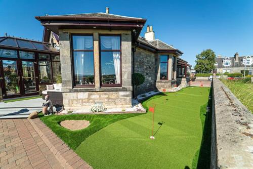 a house with a golf course in front of it at Stunning Central Villa by Golf Course & Beach in Leven-Fife