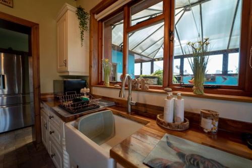 a kitchen with a sink and a counter with windows at Stunning Central Villa by Golf Course & Beach in Leven-Fife