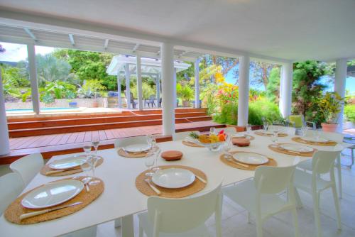 a dining room with a white table and chairs at Domaine Les hauts de Sofaia - Évasion Créole - Vue Spectaculaire in Sofaïa