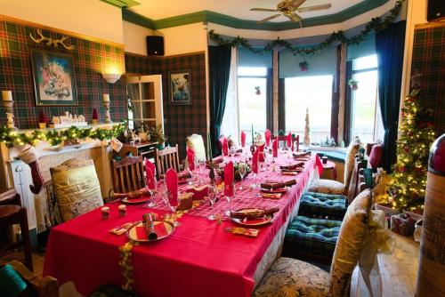 a long table with a red table cloth and a christmas tree at Stunning Central Villa by Golf Course & Beach in Leven-Fife