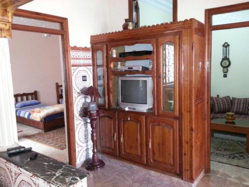 a living room with a tv in a wooden cabinet at Chez Fouzia in Essaouira