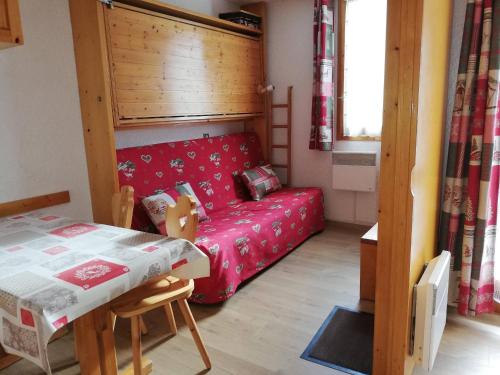 Cette petite chambre comprend un canapé rouge et une table. dans l'établissement Studio chaleureux au pied des pistes, proche commerces, 4 personnes - FR-1-356-312, à Valmorel