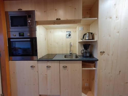 une petite cuisine avec un évier et un micro-ondes dans l'établissement Studio cosy pour 2 pers., terrasse, animaux admis - FR-1-353-12, à La Plagne