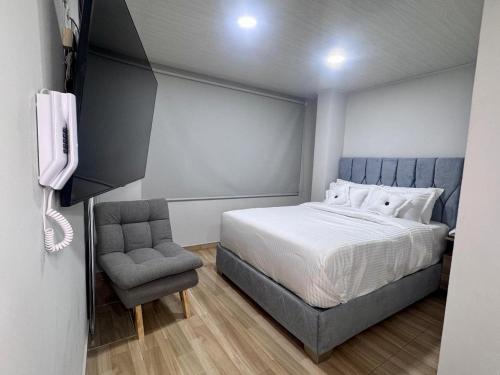 a bedroom with a bed and a chair and a phone at Hospedaje Casa Rueda in Barranquilla