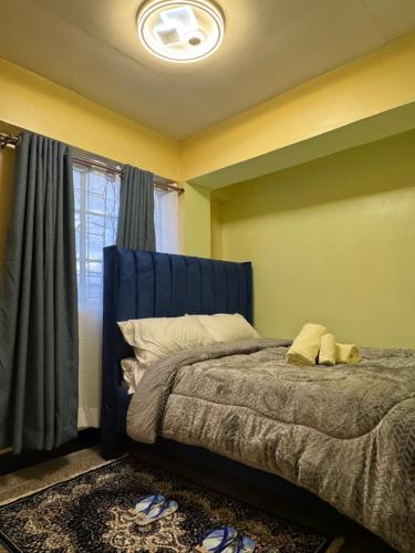 a bedroom with a bed with a blue headboard and a window at One Bedroom Modern Apartment in Nyahururu in Nyahururu