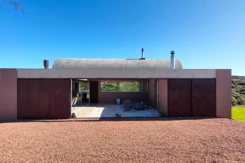 a small house with a roof on top of a field at Hermosa Chacra de Diseño, Pueblo Edén in El Eden