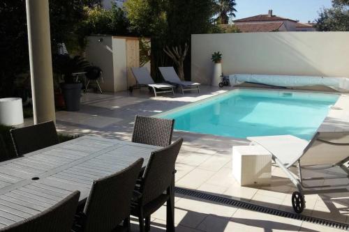 - une piscine avec une table et des chaises à côté dans l'établissement Villa contemporaine avec piscine, à Villeneuve-lès-Maguelone