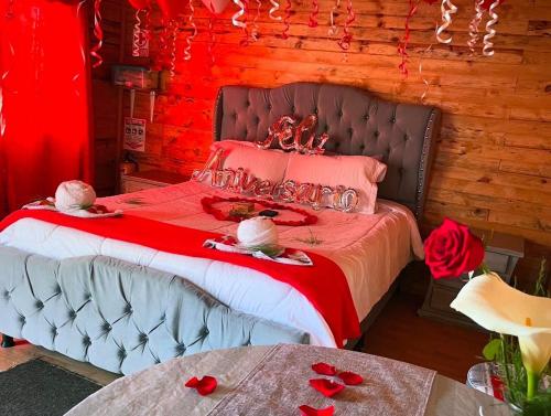 a bedroom with a bed with red sheets and roses at El Alpino Cabaña Glamping & Camping in Guatavita