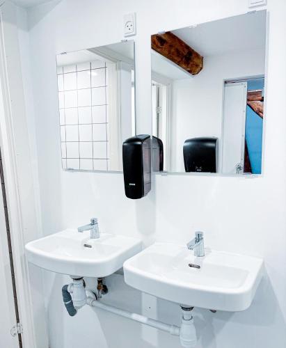 a white bathroom with two sinks and a mirror at Capsule Hotel Nyhavn63 in Copenhagen