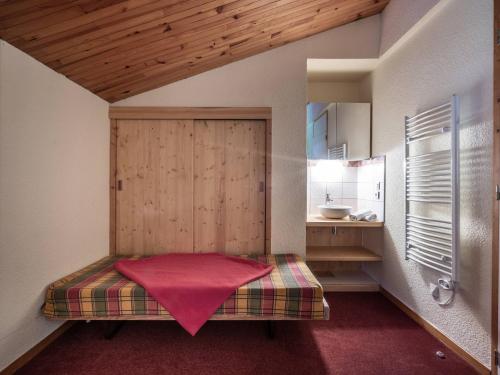 une chambre avec un lit avec une porte en bois et un lavabo dans l'établissement Duplex cosy 2 chambres, balcon, proche commerces et remontées, accepte animaux - FR-1-356-362, à Valmorel