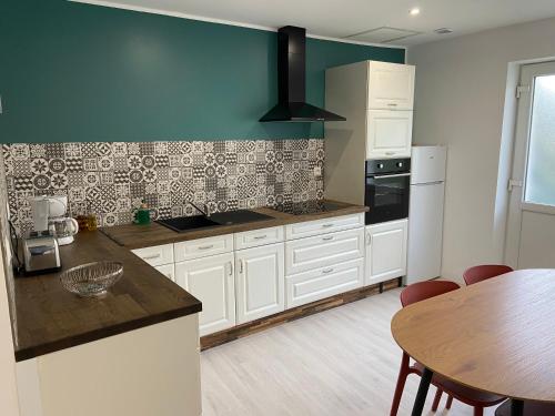 une cuisine avec des armoires blanches et une table en bois dans l'établissement Joli studio au calme, à Bruay-la-Buissière