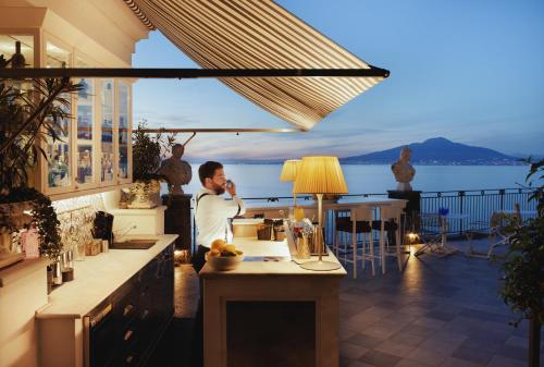 a man talking on a cell phone in a kitchen at Bellevue Syrene in Sorrento