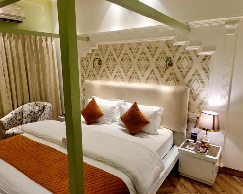 a bedroom with a bed with white sheets and orange pillows at Victorian Elegance Luxury Stays in Amritsar