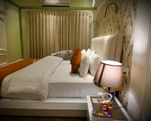 a bedroom with a bed with white sheets and pillows at Victorian Elegance Luxury Stays in Amritsar