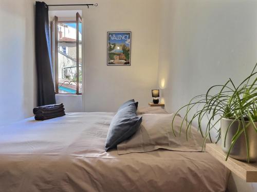 - une chambre avec un lit doté d'un oreiller et d'une plante dans l'établissement La cachette - Hypercentre, à Valence