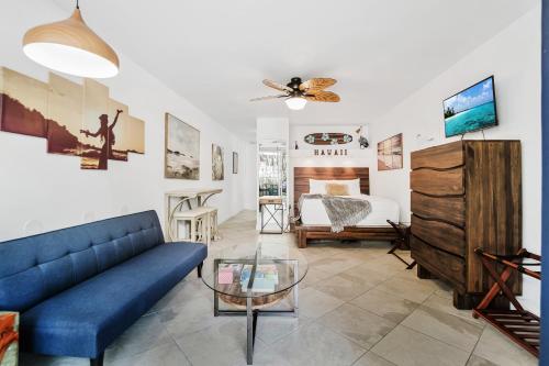 a living room with a blue couch and a bedroom at Kona Islander Inn - Prime Downtown Location with Hot Tub, Pool & Beach in Kailua-Kona