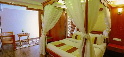 a bedroom with a canopy bed and a table at Venezia Houseboats in Alleppey