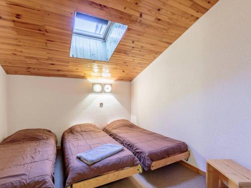 deux lits dans une chambre avec un plafond en bois dans l'établissement Duplex 5 pers, centre station La Plagne, animaux admis - FR-1-353-107, à La Plagne Tarentaise