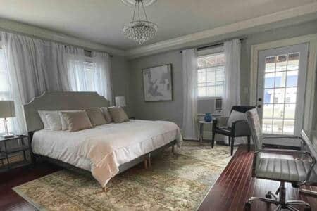 a bedroom with a bed and a chair and windows at C&J Signature Stays Downtown Apartment in Morristown