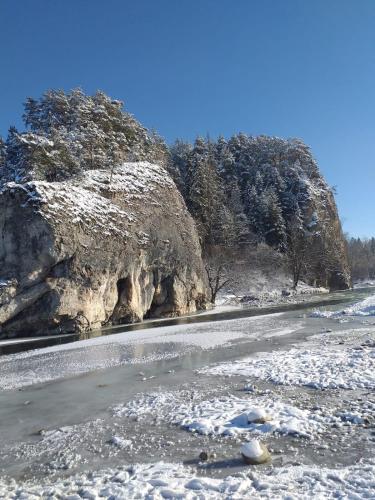 a river with snow on the ground next to a mountain at Domki Obłazówka nad Białką in Nowa Biała