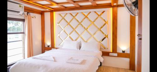 a bedroom with a bed with white sheets and a window at Venezia Houseboats in Alleppey