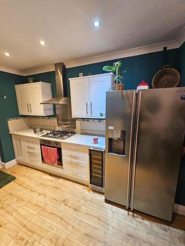 a kitchen with a stainless steel refrigerator and white cabinets at Redcar - Seafront, 6 Bedrooms, Short Stays in Redcar