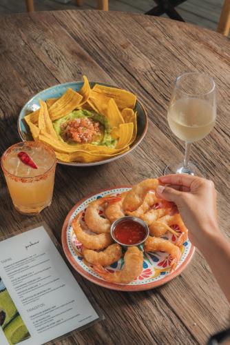 a table with a plate of onion rings and a glass of wine at Probar Suites Punta Cana in Punta Cana