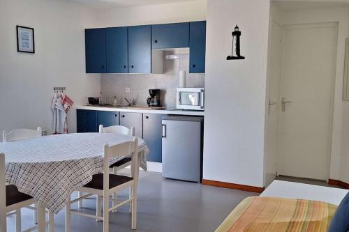 une cuisine avec des armoires bleues et une table et des chaises dans l'établissement Appartement 2 4 personnes, à Piriac-sur-Mer