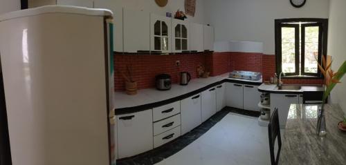 a kitchen with white cabinets and a refrigerator at BRICK VILLA in Ahangama