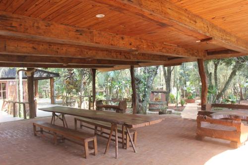 Un gran pabellón de madera con una mesa de picnic y bancos. en Six Garden Lodge, en Puerto Iguazú