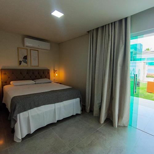 a bedroom with a bed and a large window at Flats Marina Maragogi in Maragogi