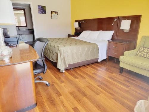 a hotel room with a bed and a desk and a chair at Cambridge Inn in Oklahoma City