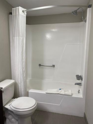 a white bathroom with a toilet and a tub and a shower at Cambridge Inn in Oklahoma City