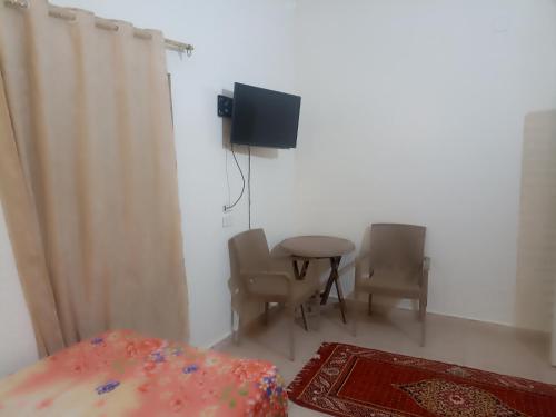 Una habitación con una mesa y sillas y un televisor. en NUBIAN MONALIZA guest house, en Asuán