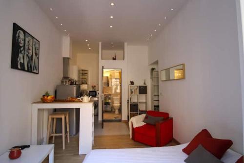 Il comprend un salon avec une chaise rouge et une cuisine. dans l'établissement Le Borniol ! Idéal ! Congrès! Central! lumineux!, à Cannes