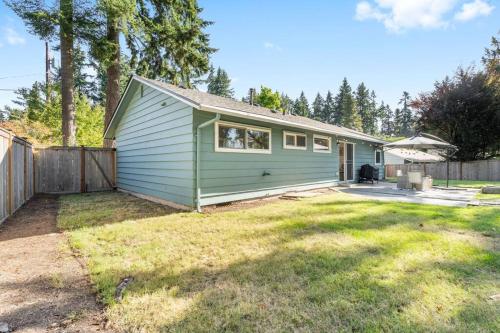 a green house with a fence and a yard at Peaceful Family Retreat Home w Firepit n Grill in Mountlake Terrace