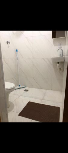 une salle de bain avec douche, toilettes et tapis dans l'établissement Casa Oliveira, à Olímpia