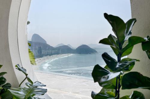a view of a beach from a window with a plant at Rio Othon Palace in Rio de Janeiro
