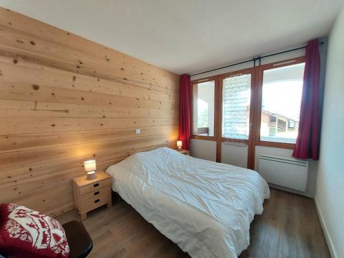sypialnia z drewnianą ścianą z łóżkiem i 2 lampami w obiekcie Appartement cosy 3 pièces avec 2 balcons, lave-vaisselle, lave-linge, à proximité des pistes - FR-1-353-126 w mieście La Plagne Tarentaise