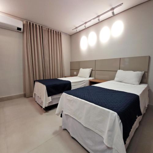 a hotel room with two beds and a window at Hotel Planalto 2 in Governador Valadares