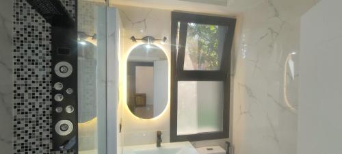 a bathroom with a sink with a mirror and a window at Premium apart avec billard et piscine in Yaoundé