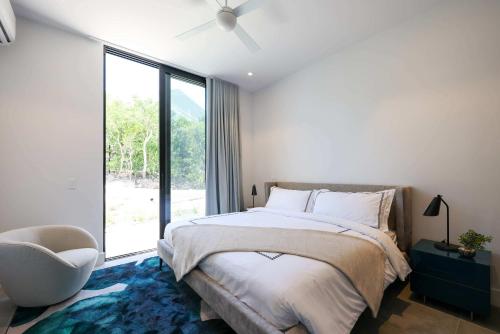 a bedroom with a bed and a chair and a window at Villa Pluto 4 Bedroom with Private Pool Oceanfront in Providenciales