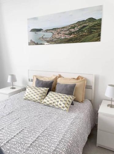 a bedroom with a bed with pillows and a painting at Aligus 2 Uma Horta na Horta, Faial, Açores in Horta